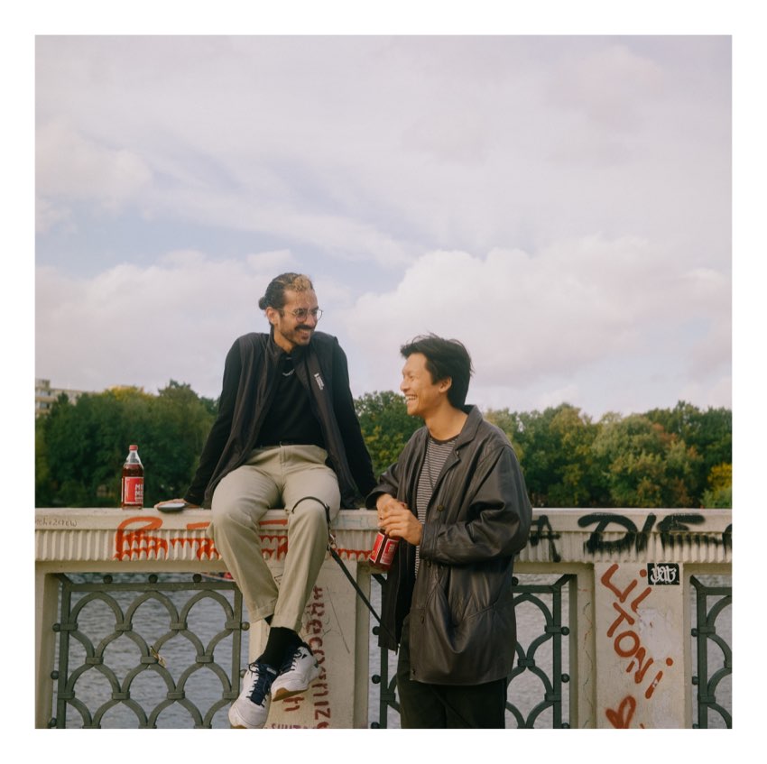 Two friends talking on a bridge railing
