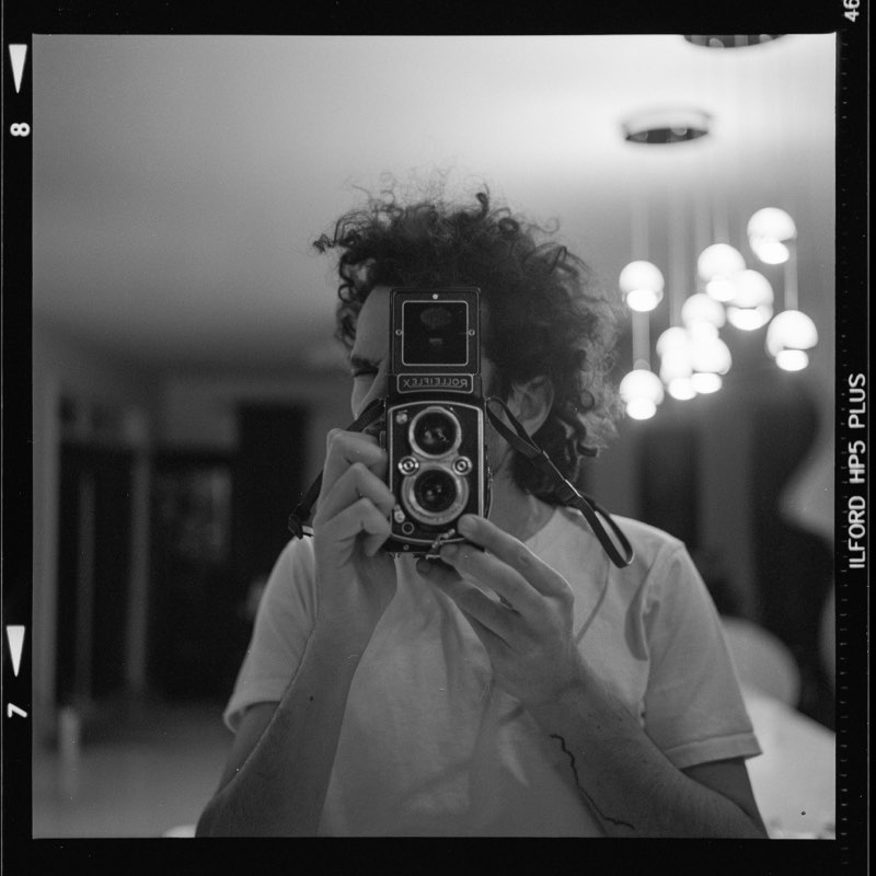 Karam photographing himself in a mirror with a Rolleiflex camera, on black and white film