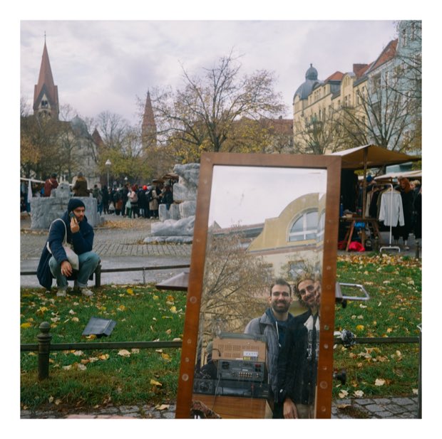 A mirror propped at a flea market reflecting two friends