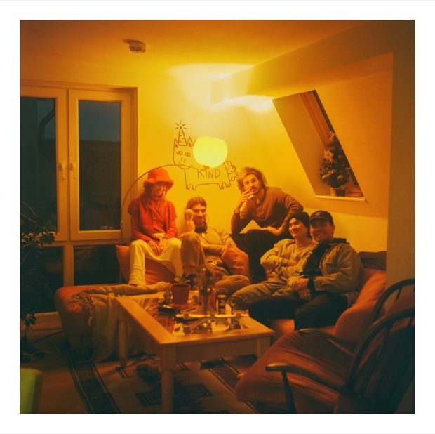 A living room bathed in orange light with five friends on the sofa
