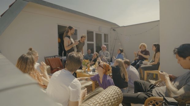 A rooftop full of people talking in the sun