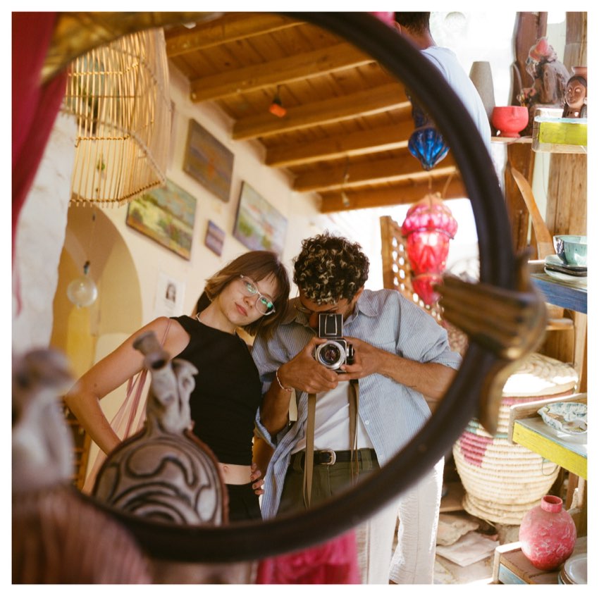 Karam and a friend reflected in a round mirror in a shop