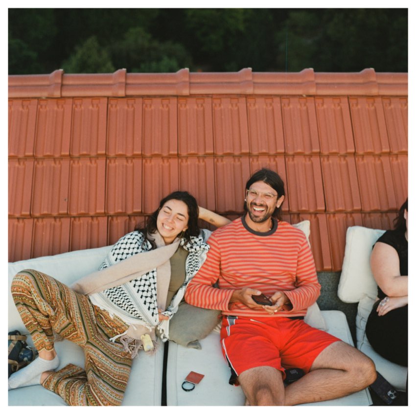 Two friends laughing on a rooftop sofa